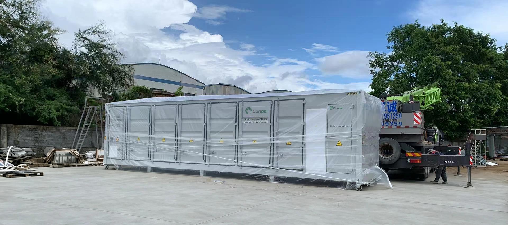 Large plastic-wrapped energy storage container delivered by crane truck at an outdoor industrial site in Eswatini.