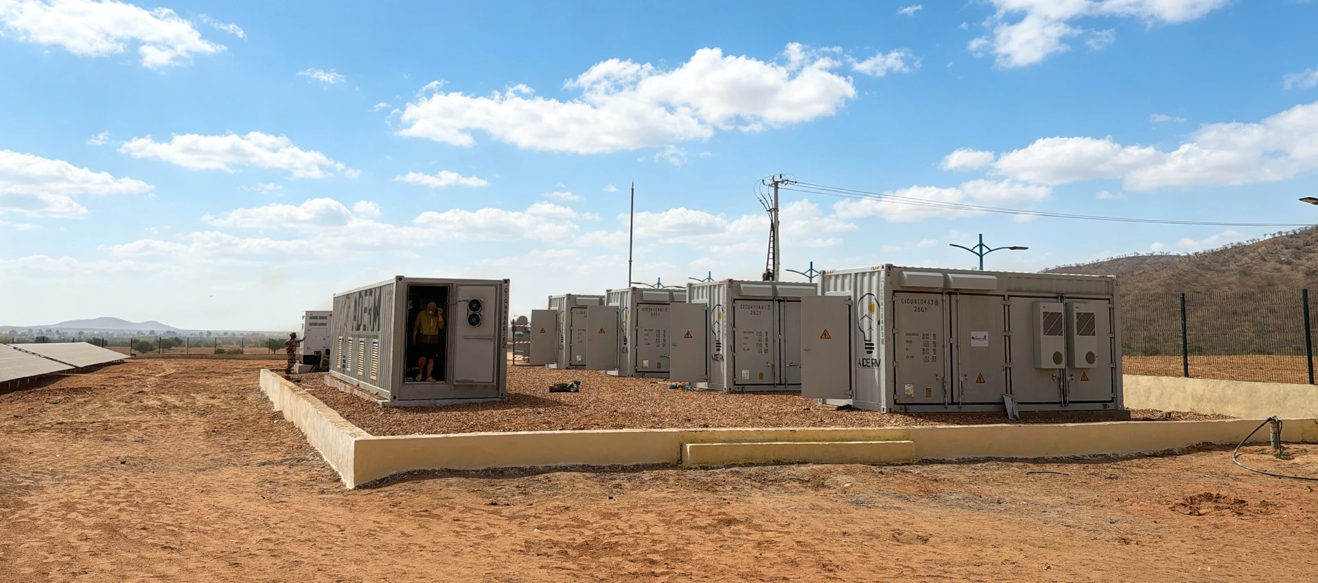Wide shot of containerized energy storage systems and solar installations deployed in a desert microgrid project in Chad.