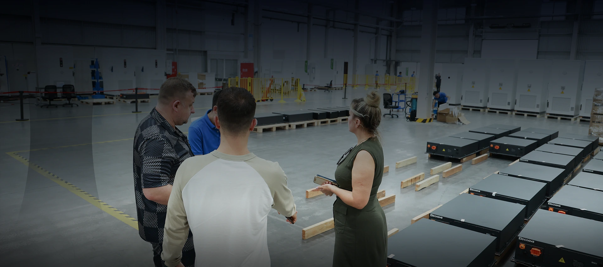 International clients touring the BESS production facility while reviewing battery packs on the factory floor.