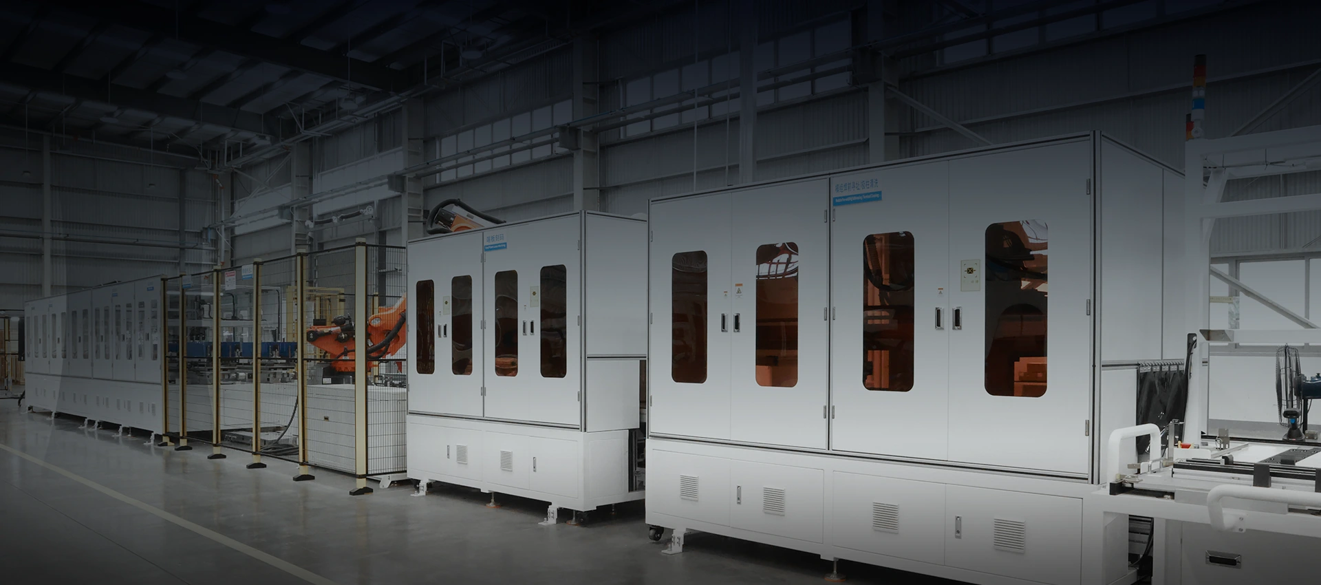 Automated manufacturing enclosures and robotic arms along an industrial assembly line for BESS production.