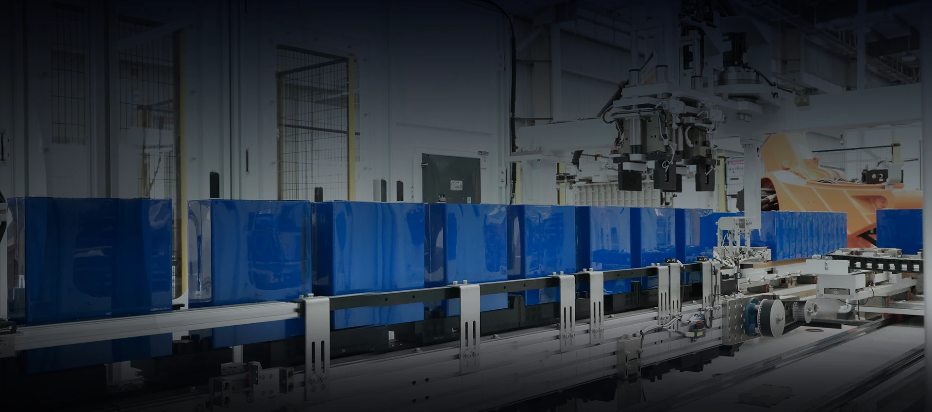 Blue prismatic battery cells aligned on an automated conveyor system during battery pack assembly.