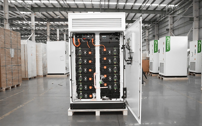 Open front door of the Sunpal ECO-E101WX energy storage cabinet revealing stacked rack-mounted battery modules, cooling fans, and internal wiring inside a warehouse setting.