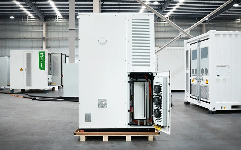 Rear view of a white Sunpal commercial energy storage cabinet with an open lower access door showing internal wiring and integrated cooling fans inside a factory.
