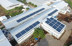 Aerial view of solar photovoltaic panels installed across the rooftops of an industrial factory facility.