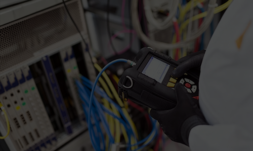 Technician using a handheld testing device to inspect and verify hardware equipment system wiring.