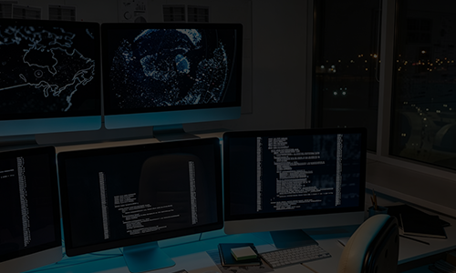 Multiple computer monitors displaying real-time system data, code, and global tracking maps in a dark control center.