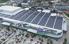 Aerial view of a large retail shopping center with a massive rooftop solar PV installation and adjacent parking lot.
