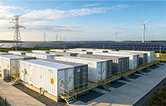 Utility-scale battery storage containers integrated with solar PV panels, wind turbines, and high-voltage power lines.