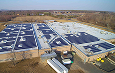 Aerial view of a commercial building rooftop installed with a large photovoltaic solar panel array.
