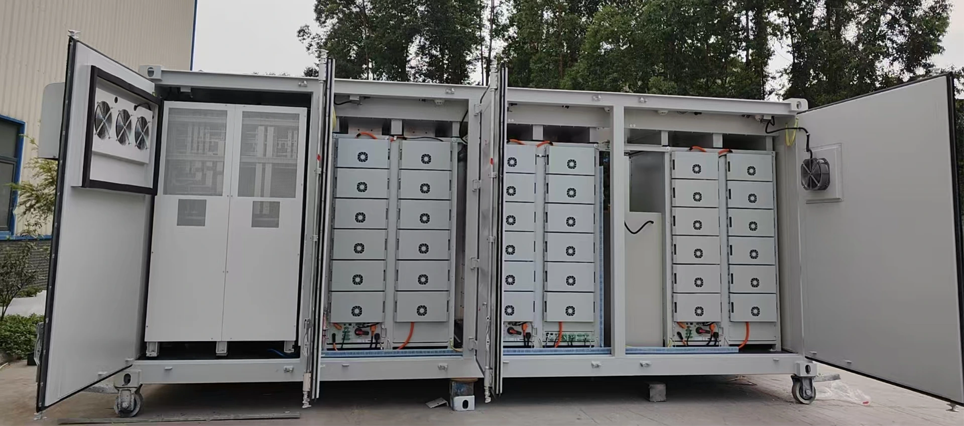 A large white outdoor energy storage container with its doors open, showing battery racks, control cabinets, and cooling systems.